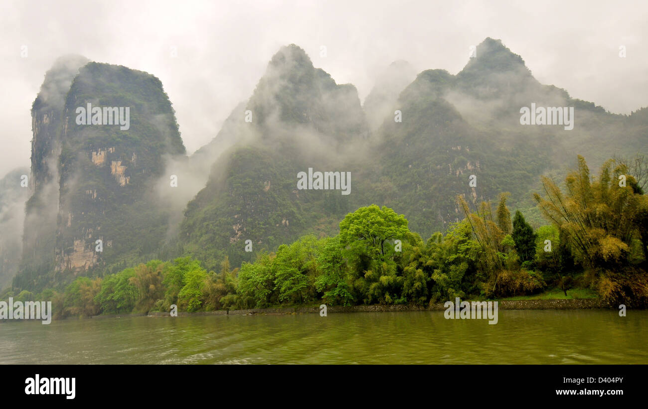 Tiefliegende Wolken Leichentuch Kalkstein Outcroppings an einem verregneten Tag - Li-Fluss, Guilin, China Stockfoto
