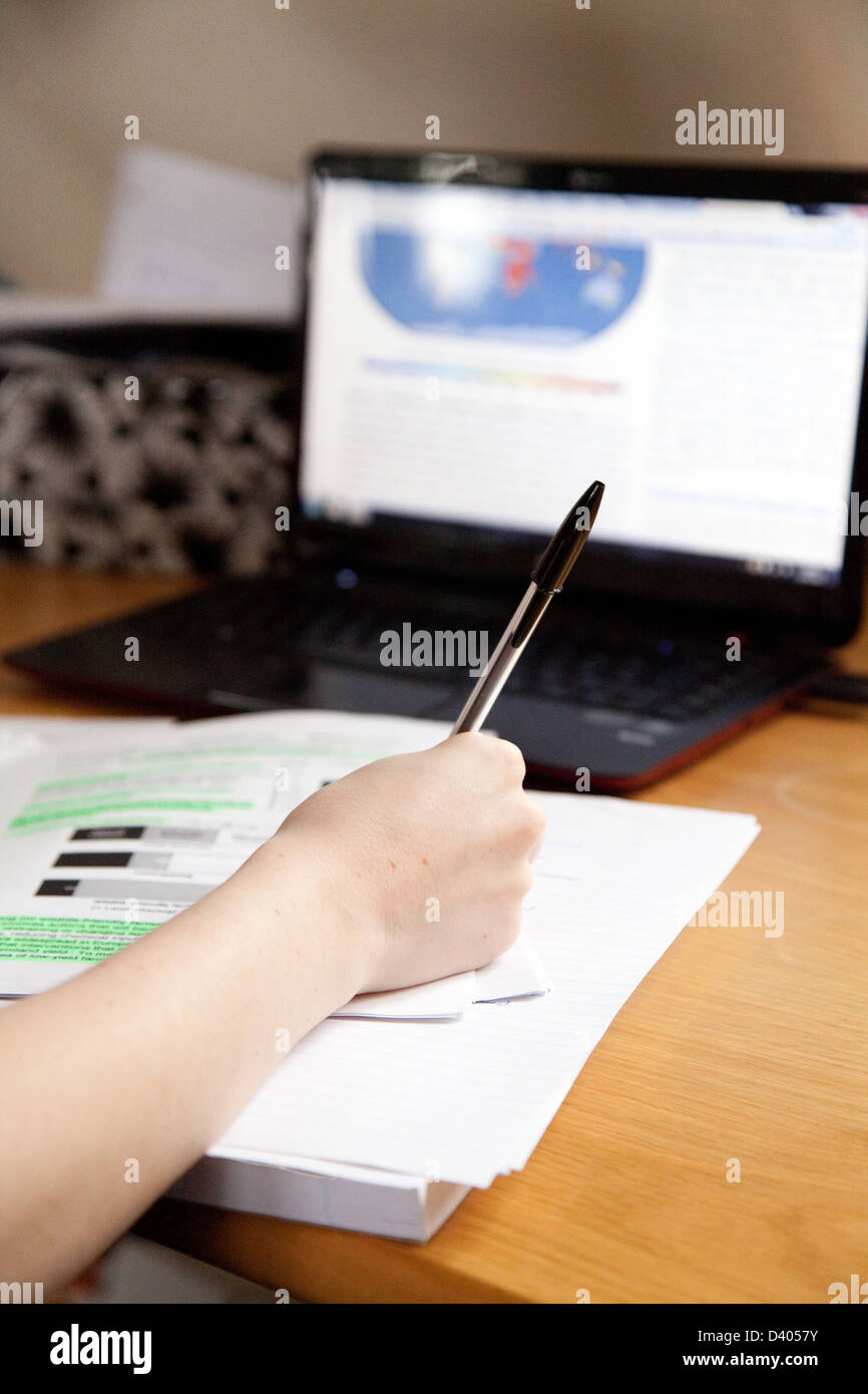 Studiert am Schreibtisch-Close up von Hand mit Stift, Papier und Laptop-Computer, UK Stockfoto