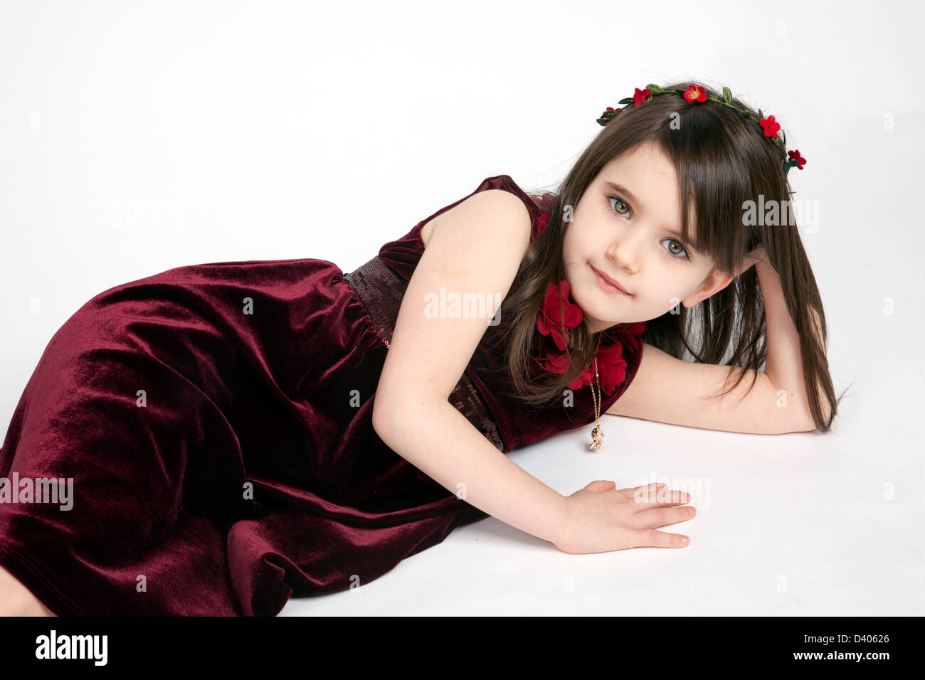 Hübsches kleines Mädchen posiert in einem Studio gedreht trägt ein tief roter Samt-Kleid Stockfoto