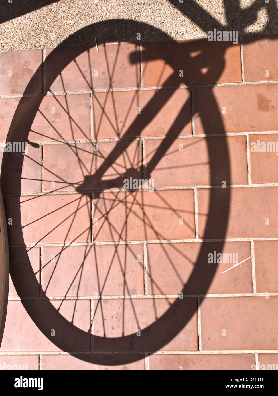 Fahrrad-Rad-Schatten auf Bodenfliesen Stockfoto