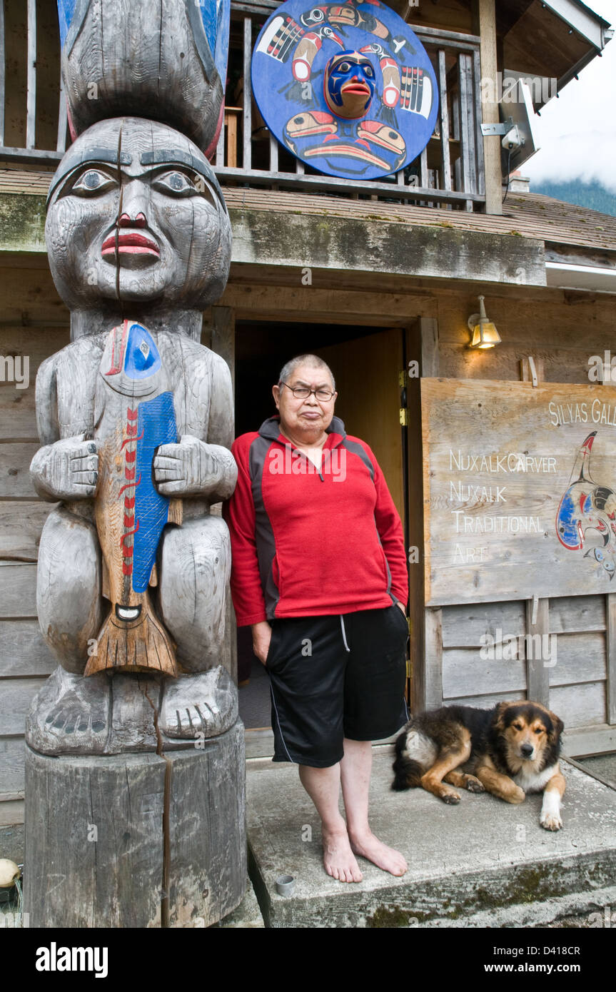 Porträt eines Nuxalk Carver und älteren Stand neben seinem Totempfahl in der Heimat behalten Stadt von Bella Coola, Britisch-Kolumbien, Kanada. Stockfoto