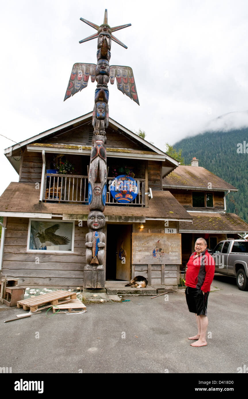 Porträt eines Nuxalk Carver und älteren Stand neben seinem Totempfahl in der Heimat behalten Stadt von Bella Coola, Britisch-Kolumbien, Kanada. Stockfoto