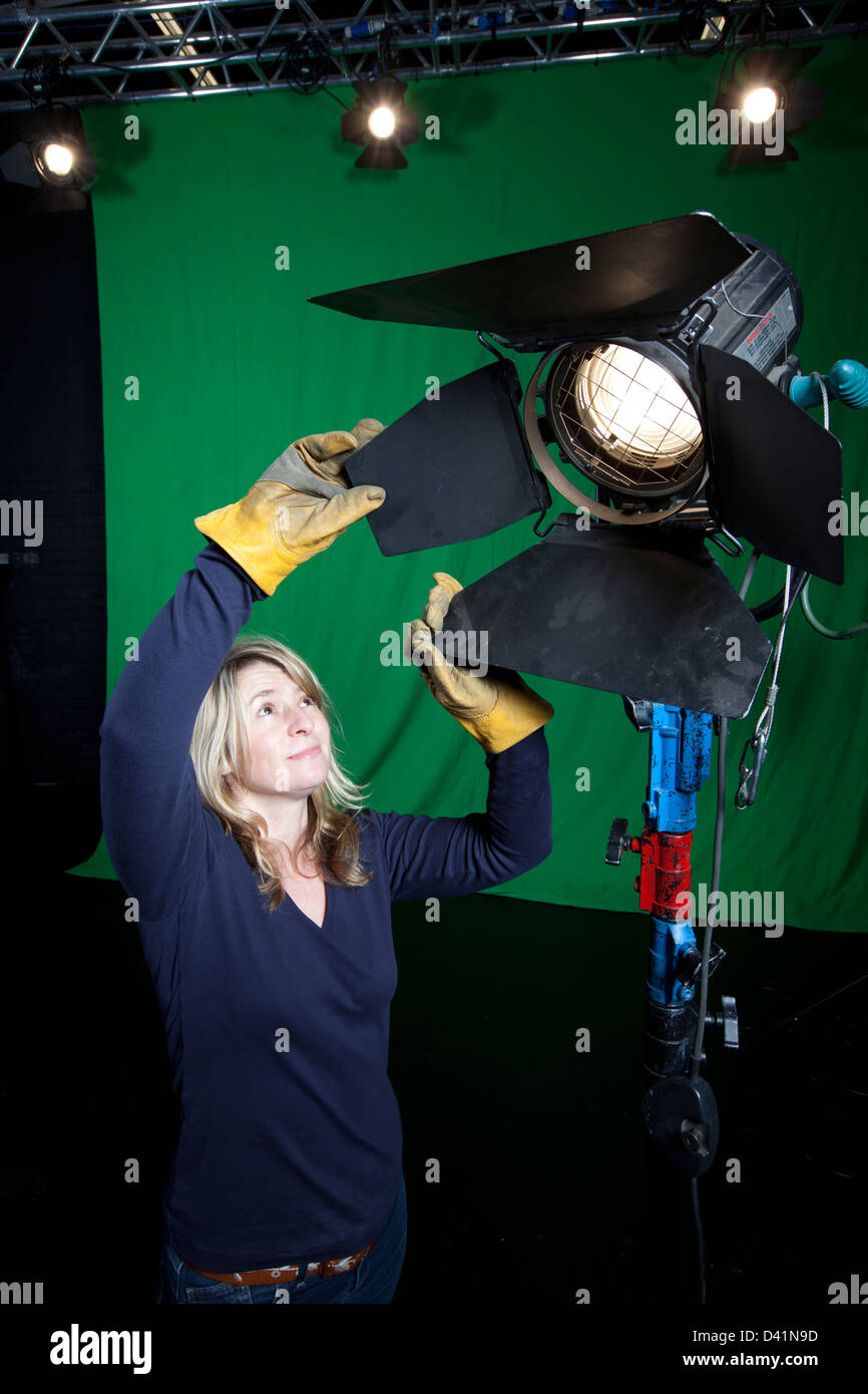 Weibliche Lichttechniker passt die Scheunentore auf ein Licht im Inneren ein Fernsehstudio. Stockfoto