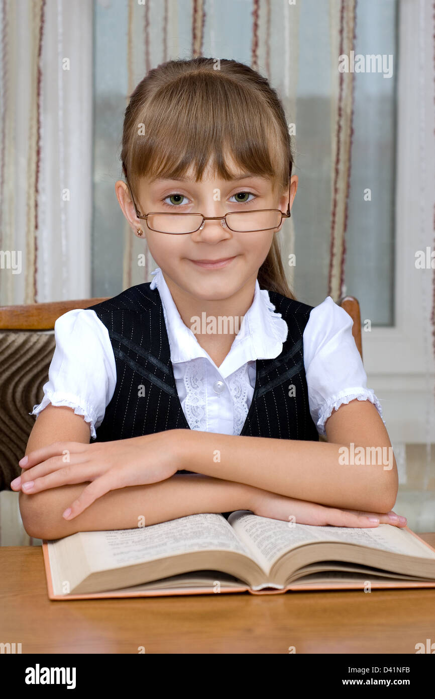 Das Schulmädchen in Schauspielen liest das dicke Buch Stockfoto