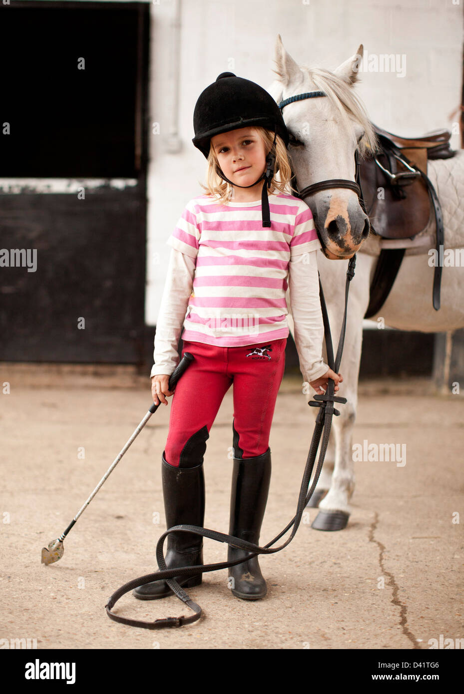 Junge Mädchen, die Zügel des Ponys im Stall, London, UK Stockfoto