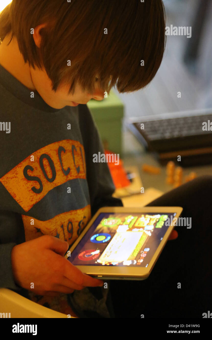 Jungen spielen Game On iPad Mini England Stockfoto