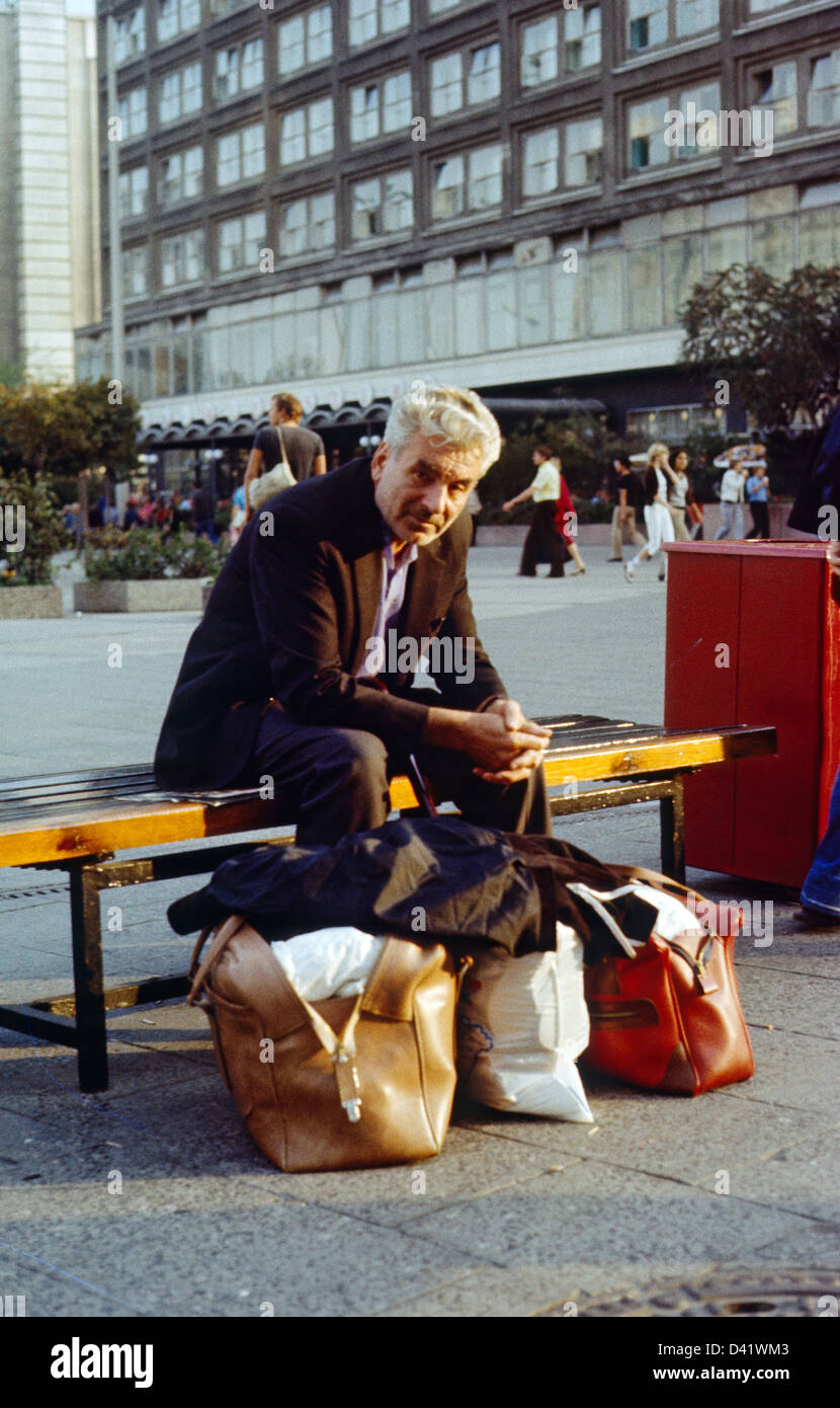 Berlin, DDR, Senior sitzt nachdenklich auf einer Straße Bank Stockfoto