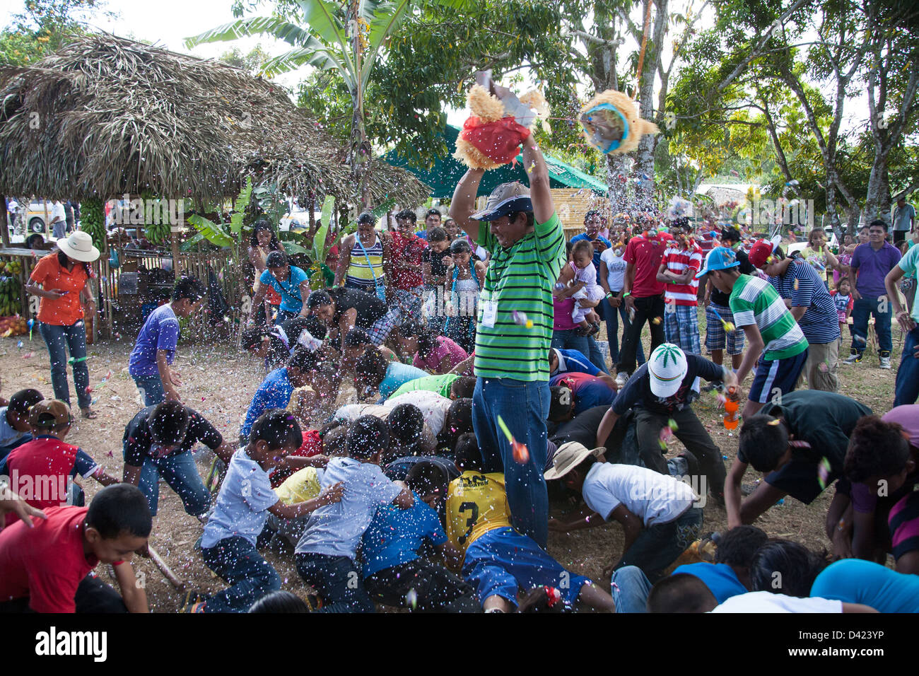 Ein gebrochenen offenen Pinata und ein Kerl Duschen den Inhalt wie Süßigkeiten und Spielzeug unter den Kindern bei einem Festival in Panama. Stockfoto