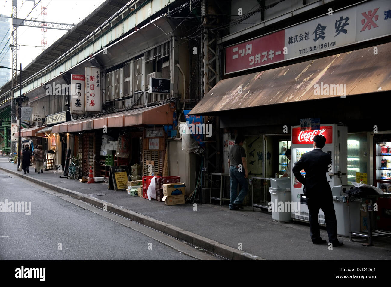 Geschäfte und Restaurants teilen Raum nebeneinander unter der Hochbahn-Spuren in Tokios Yurakucho Bezirk. Stockfoto