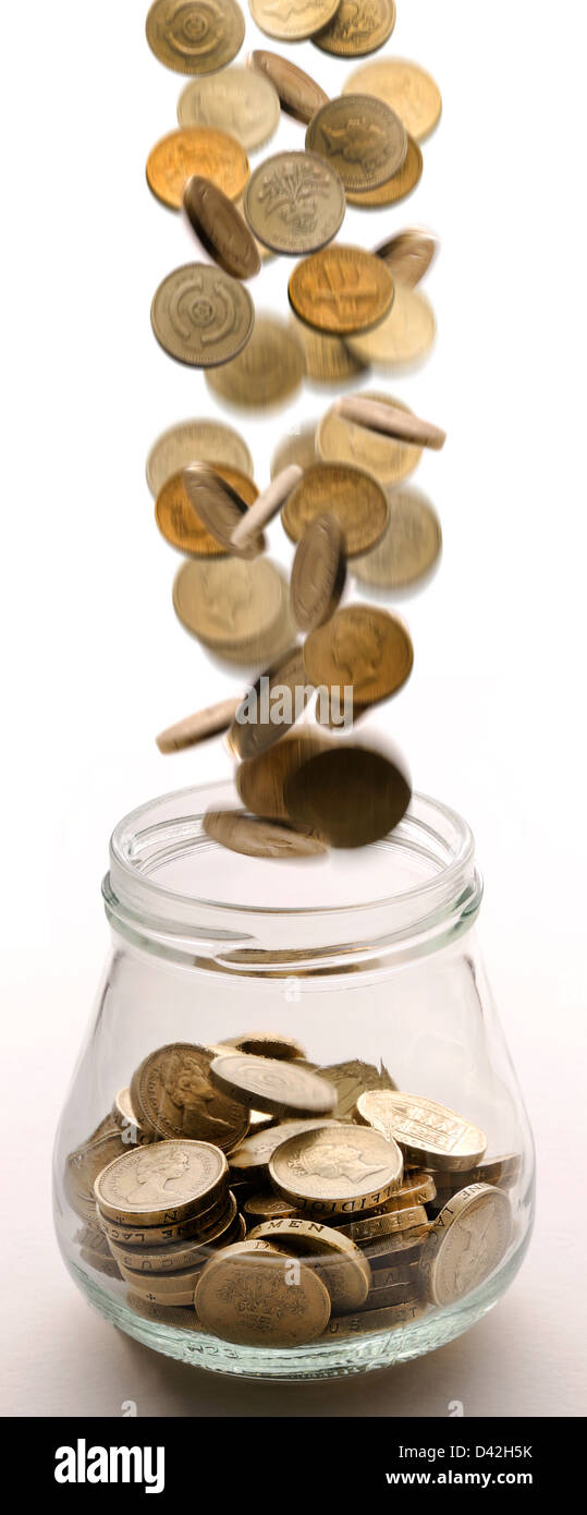 Pfund-Münzen fallen in einem Glas Stockfoto