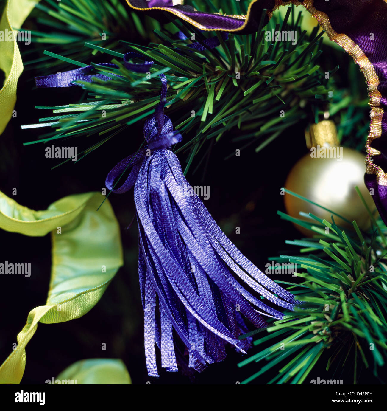 Nahaufnahme der blaue Seide Quaste an faux Weihnachtsbaum Zweig mit gold Christbaumkugel und lindgrün Seidenband Stockfoto