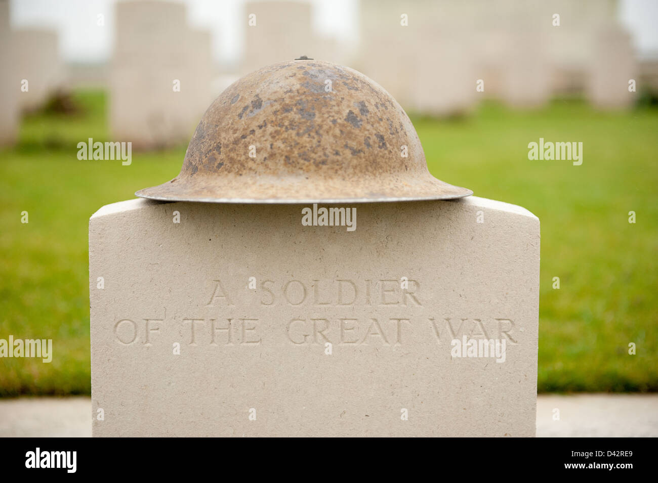 Leere Grabstein in einem Commonwealth Soldatenfriedhof mit einem britischen militärischen Helm auf der Oberseite - A SOLDIER OF THE GREAT WAR platziert. Stockfoto