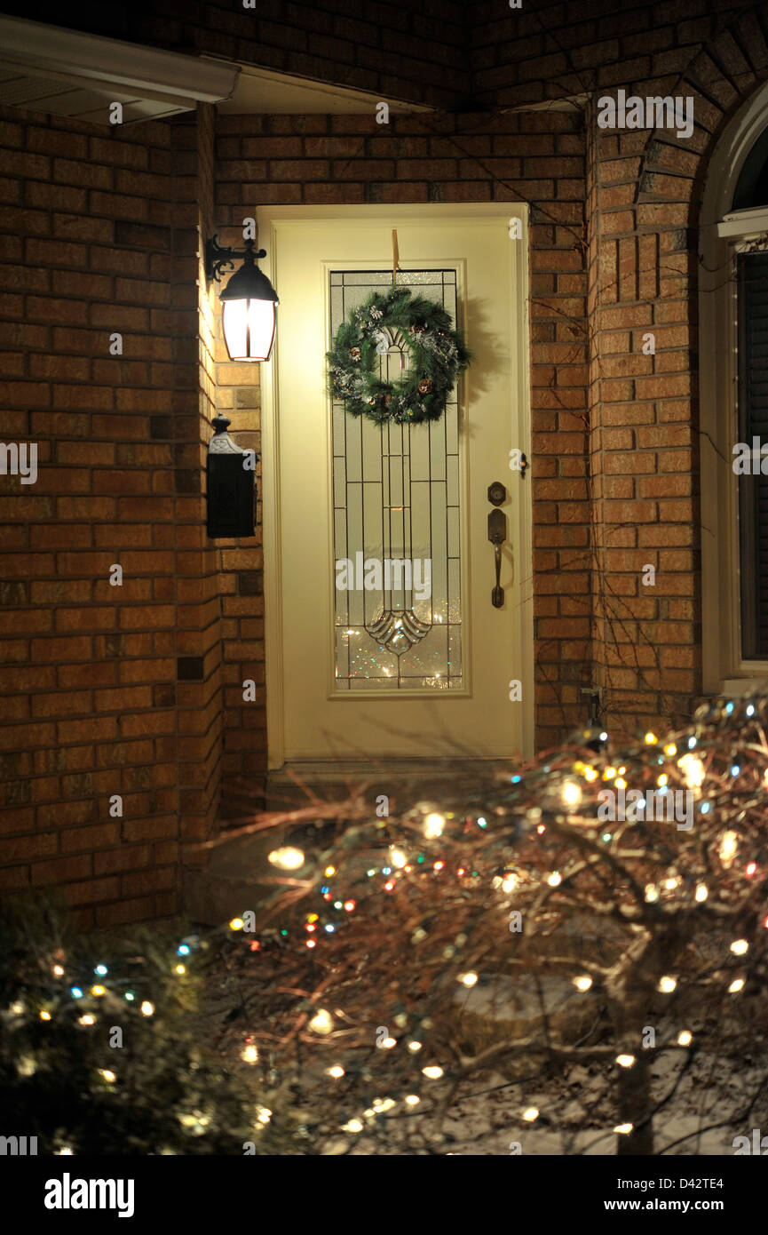 Einfamilienhaus-Tür mit Weihnachtsdekoration mit beleuchtet. Stockfoto