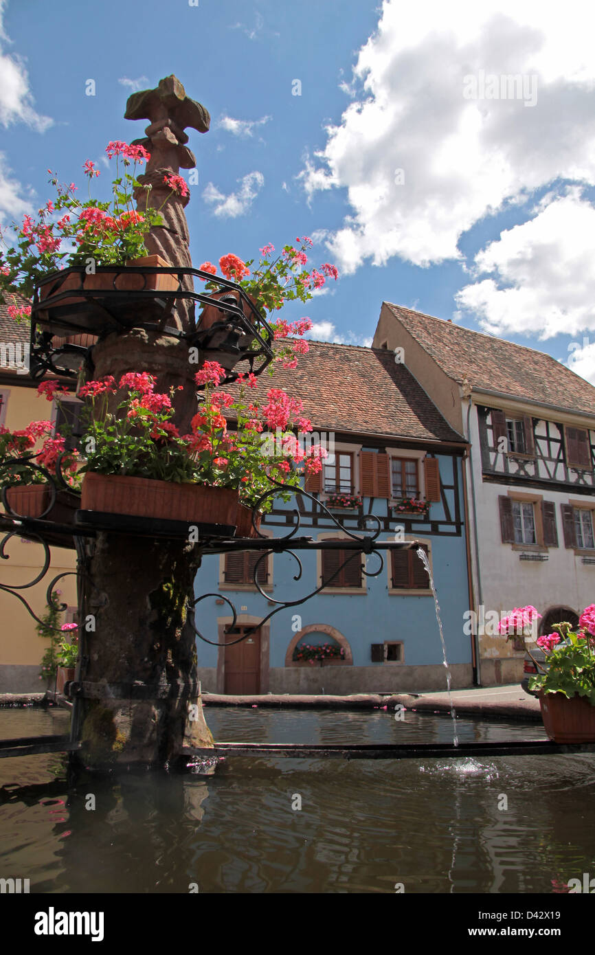 Dorfbrunnen mit mit blauen Fachwerkhaus im Elsass/Frankreich Stockfoto