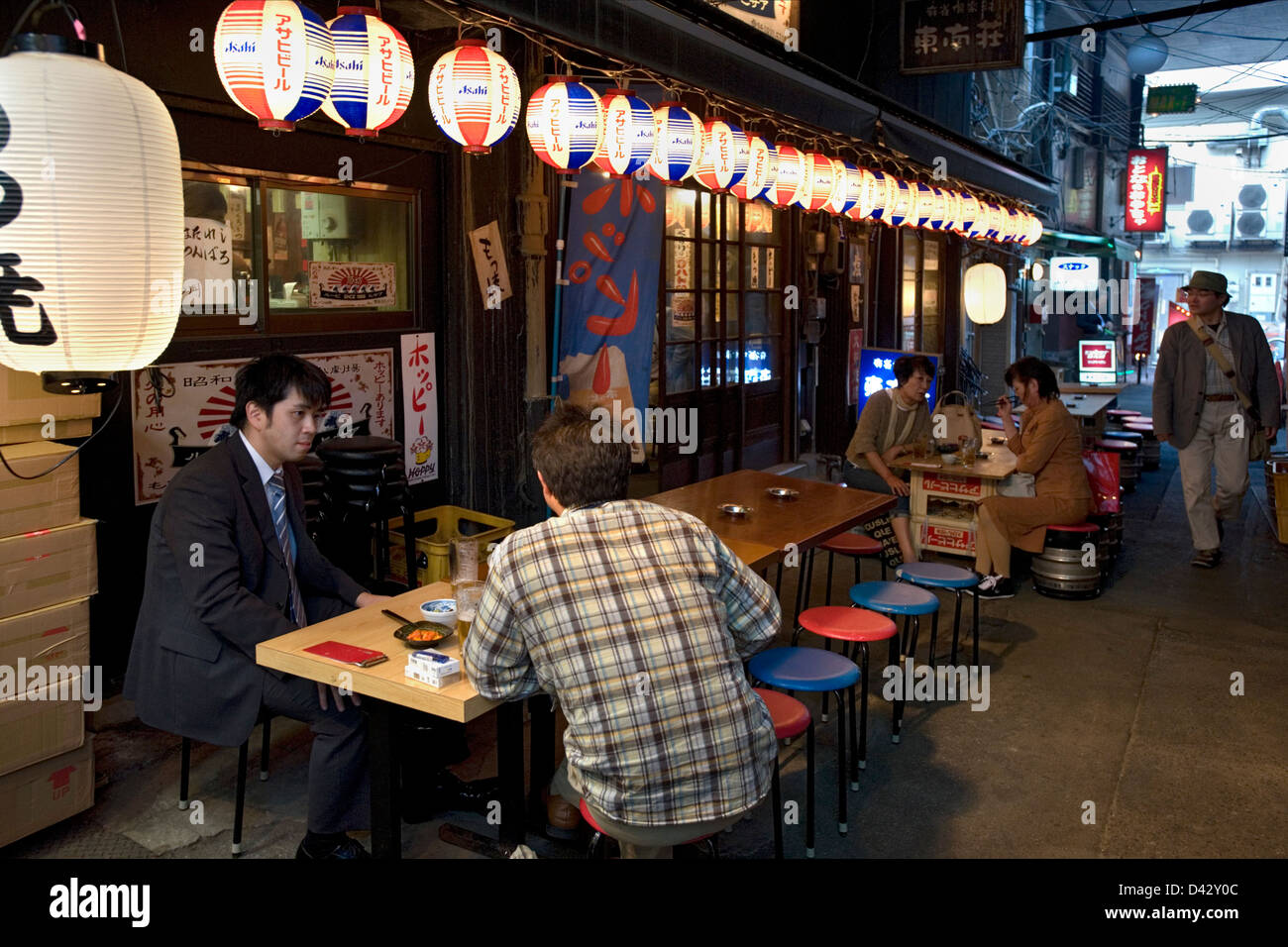 Gönner mit Bier und Brotzeit am Bürgersteig Izakaya trinken Einrichtung versteckt unter der Hochbahn in Okachimachi, Tokio Stockfoto