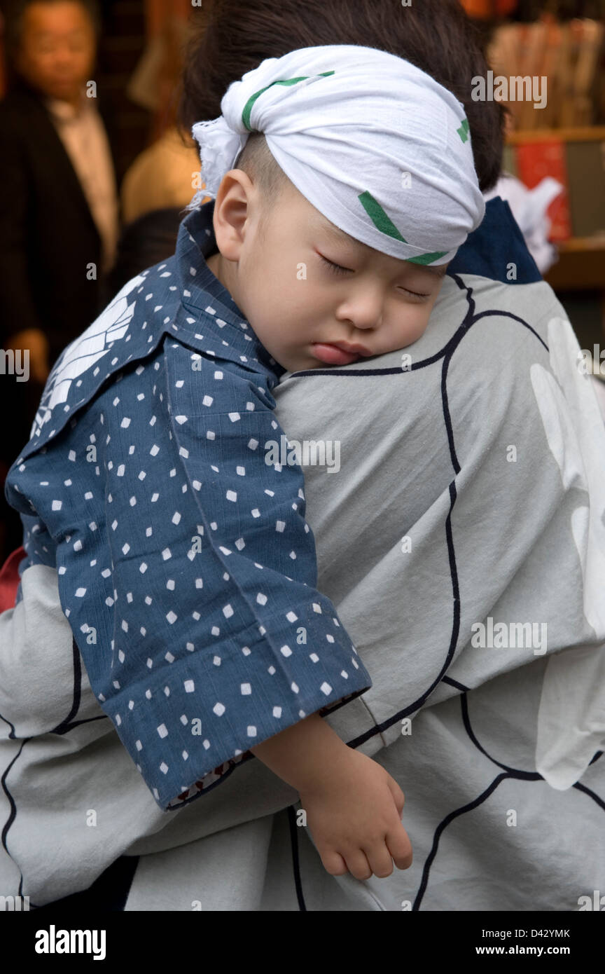 Ein kleine japanische Festival Teilnehmer hat genug für den Tag und hat beschlossen, ein Nickerchen auf seines Vaters Schulter. Stockfoto