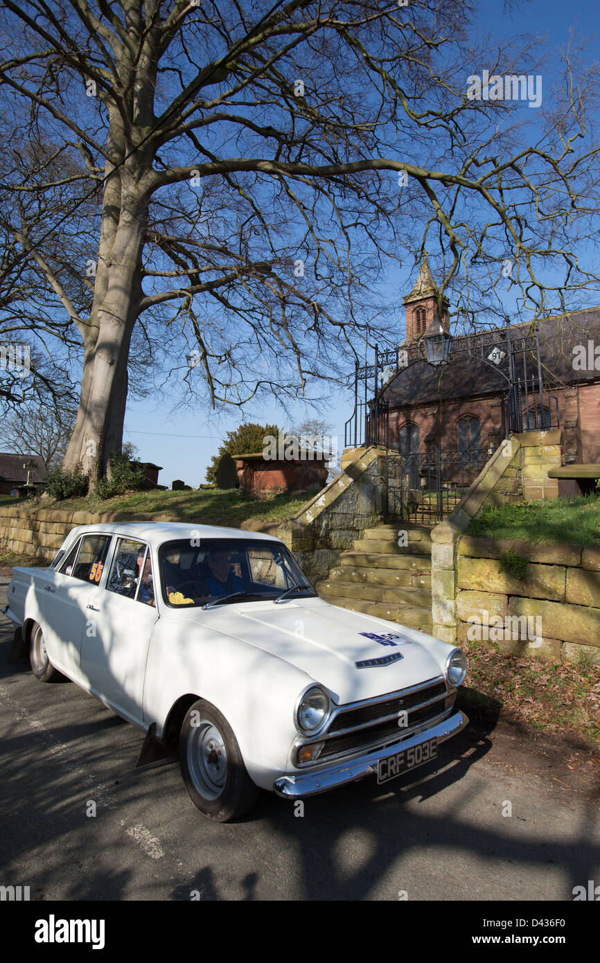 Dorf von Coddington, England.  Malerische Aussicht auf einen weißen 1967 Mk1 Ford Cortina GT durch das Dorf Coddington. Stockfoto