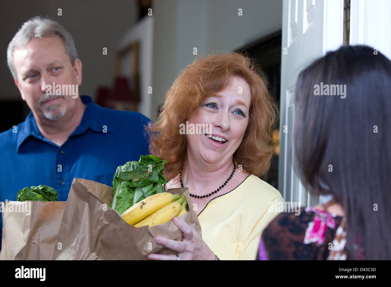 Frau liefert Taschen von Lebensmitteln an die Heimat eines Menüs auf ihre Glück-paar, die von ihren Jobs entlassen worden. Stockfoto