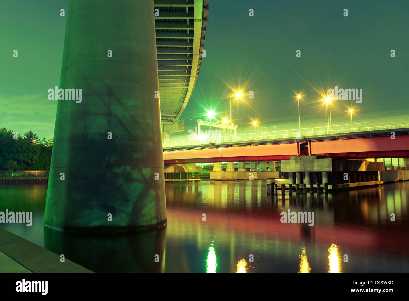 Support für riesige Highway im Vordergrund mit roten Brücke beleuchtet bei Nacht in Tokio, Japan Stockfoto