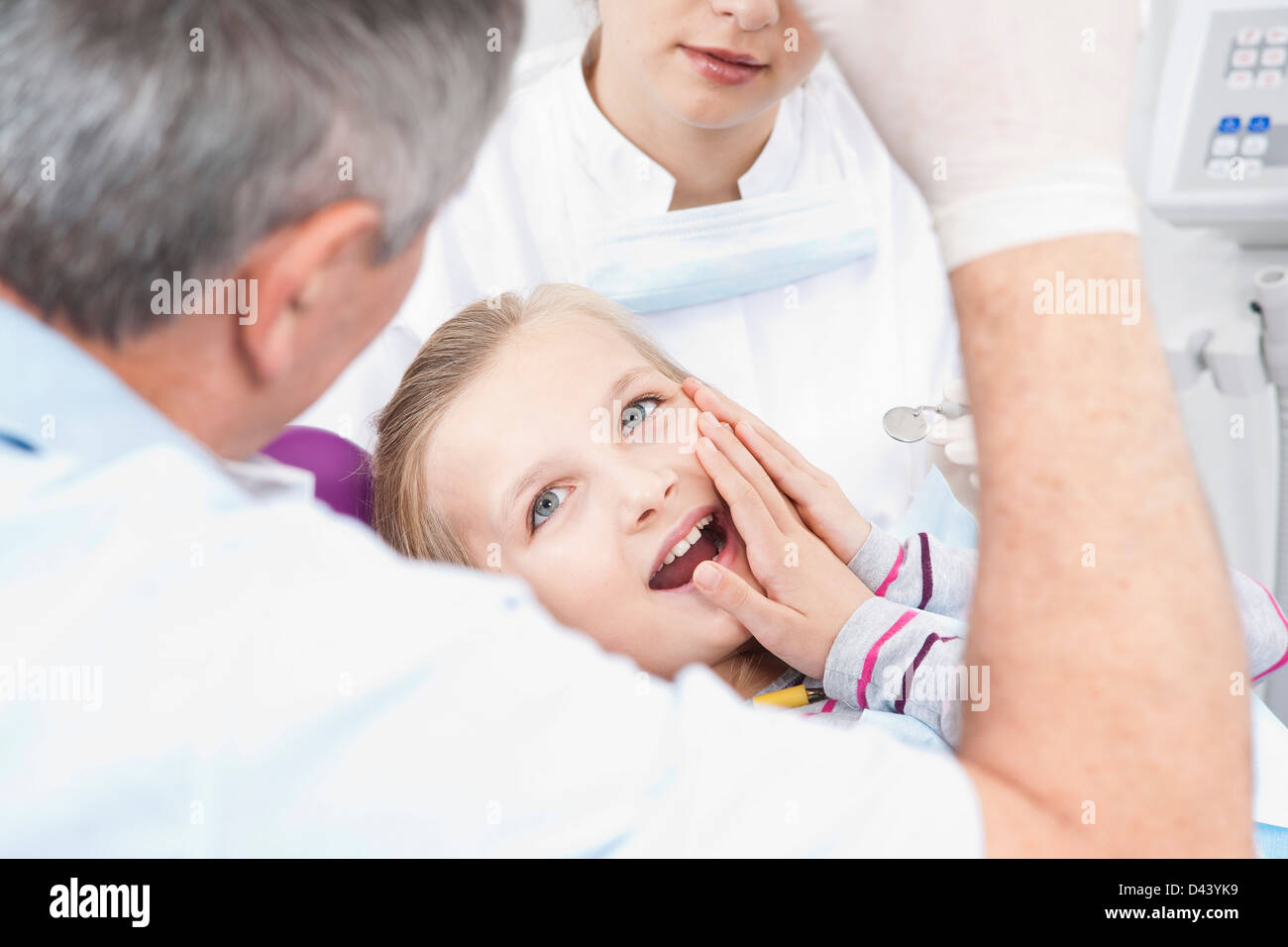 Mädchen, die Berührung der Wange mit Zahnarzt und Hygieniker in Dental Office, Deutschland Stockfoto