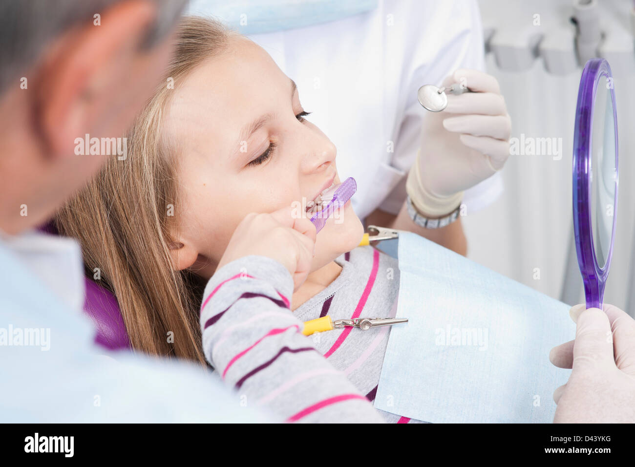 Mädchen Zähneputzen mit Zahnarzt und Hygieniker während Termin, Deutschland Stockfoto