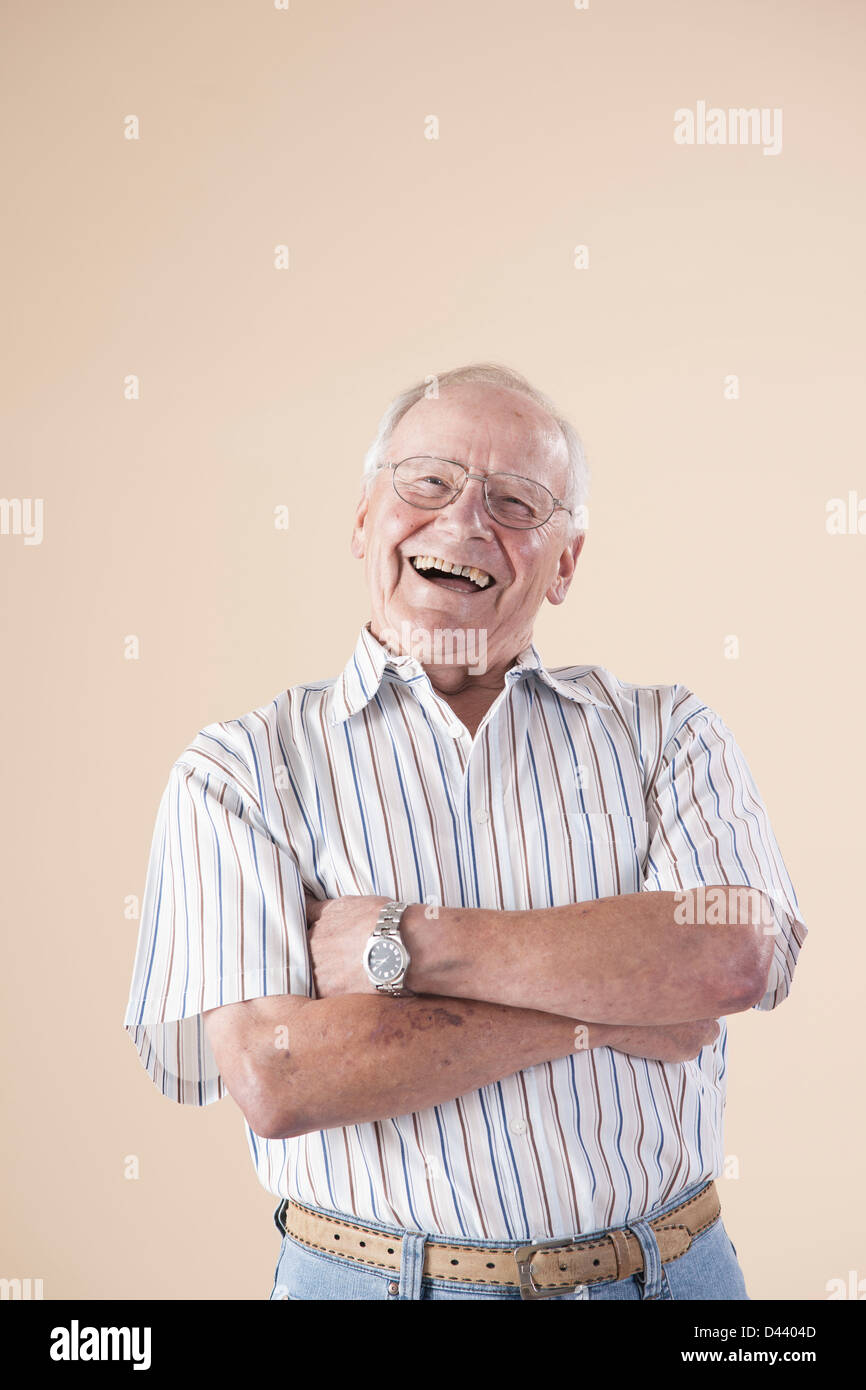 Porträt von Senior Mann mit Aviator Brillen, Kamera Lachen im Studio auf Beige Hintergrund betrachten Stockfoto