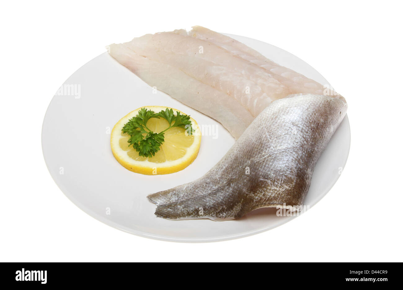 Rohe Pollock Fischfilet auf einem Teller mit Zitrone und Petersilie isoliert gegen weiß Stockfoto