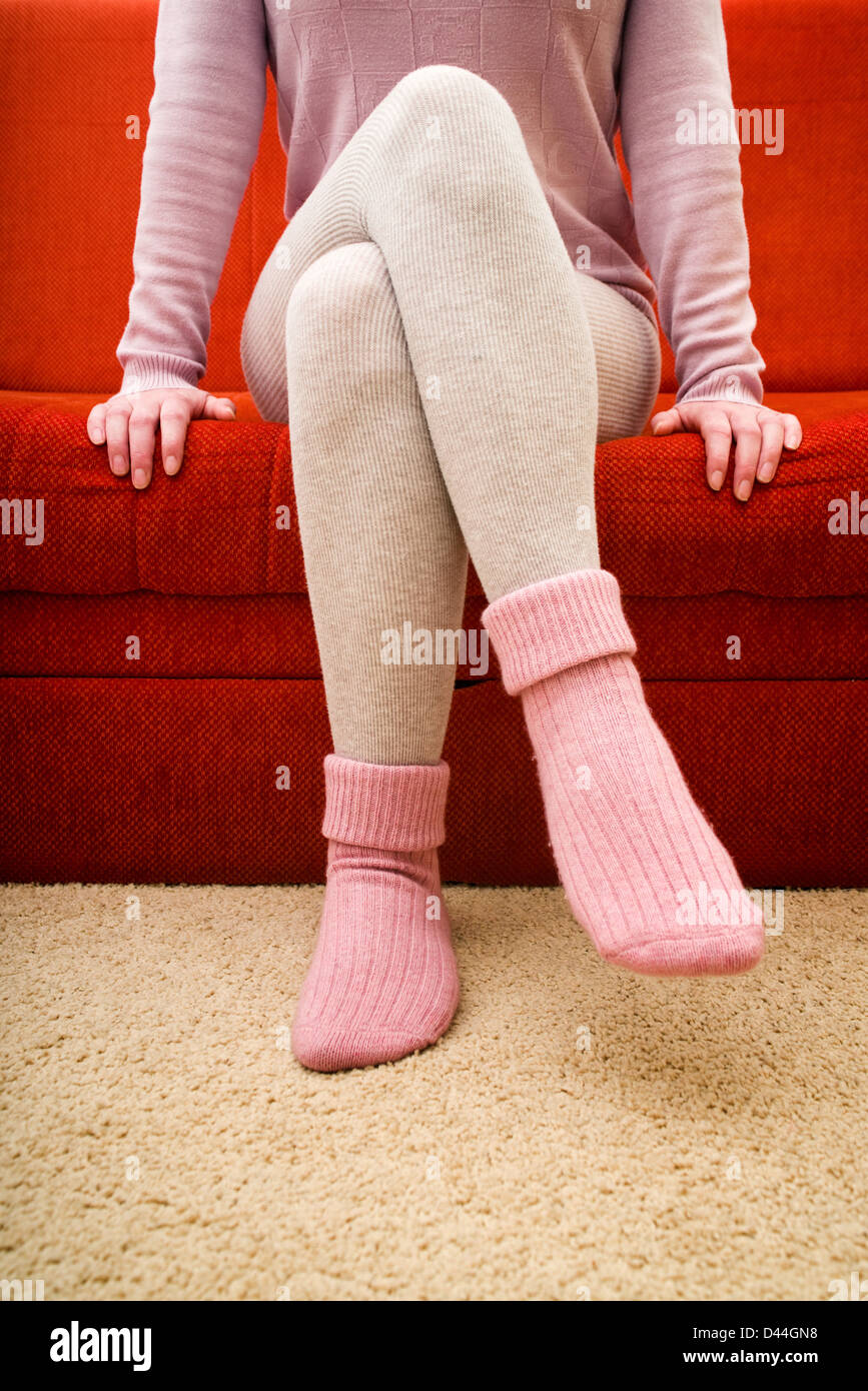 Weibliche Beine tragen schöne warme rosa Wollsocken zu Hause. Stockfoto