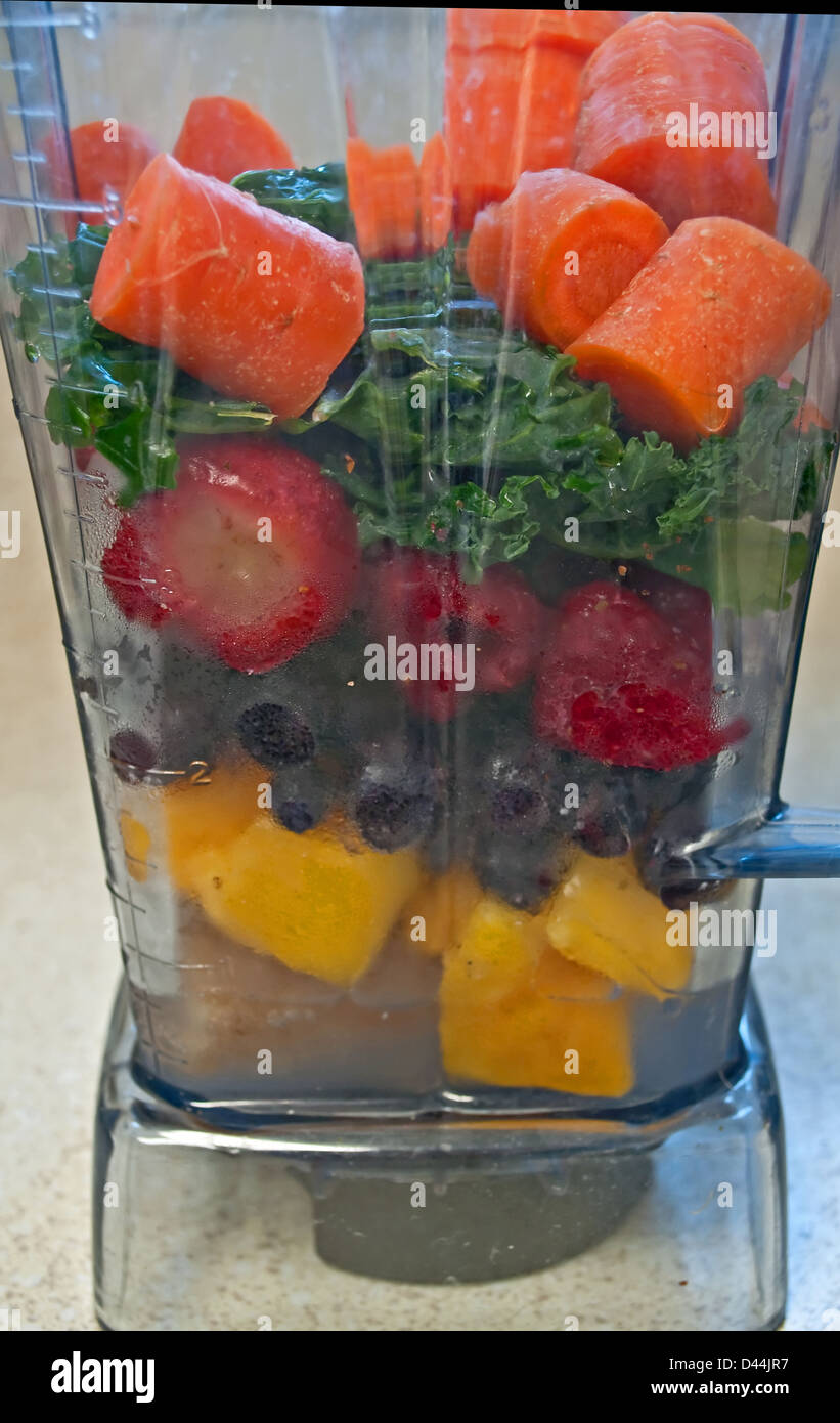 Stillleben mit frischem Obst und Gemüse in einen Mixer bereit, einen Smoothie trinken zu machen. Karotten, Grünkohl, Heidelbeeren, Erdbeeren Stockfoto