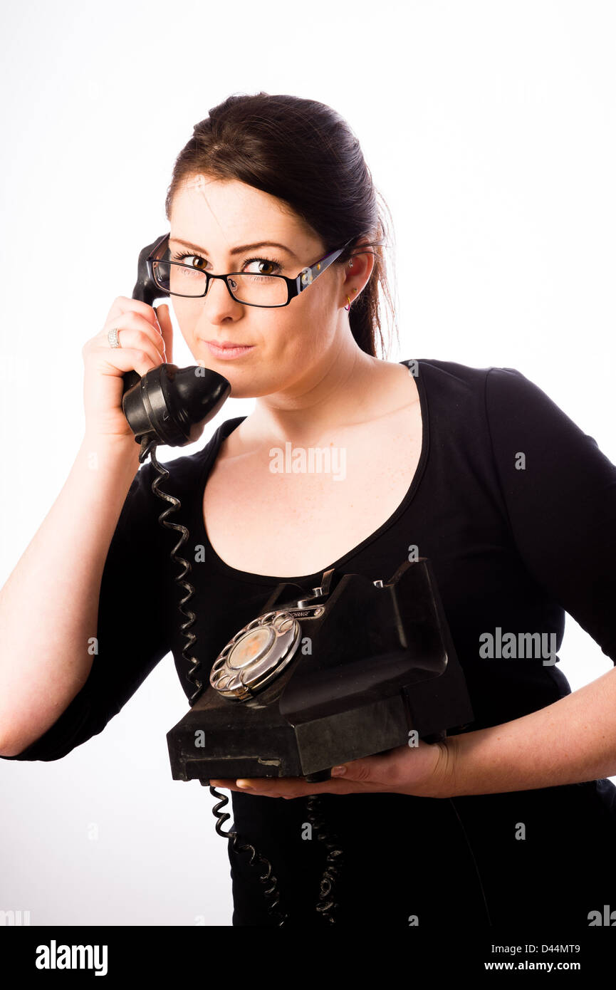 Eine junge Frau, braune Haare Holding mit einem altmodischen Telefon, UK Stockfoto