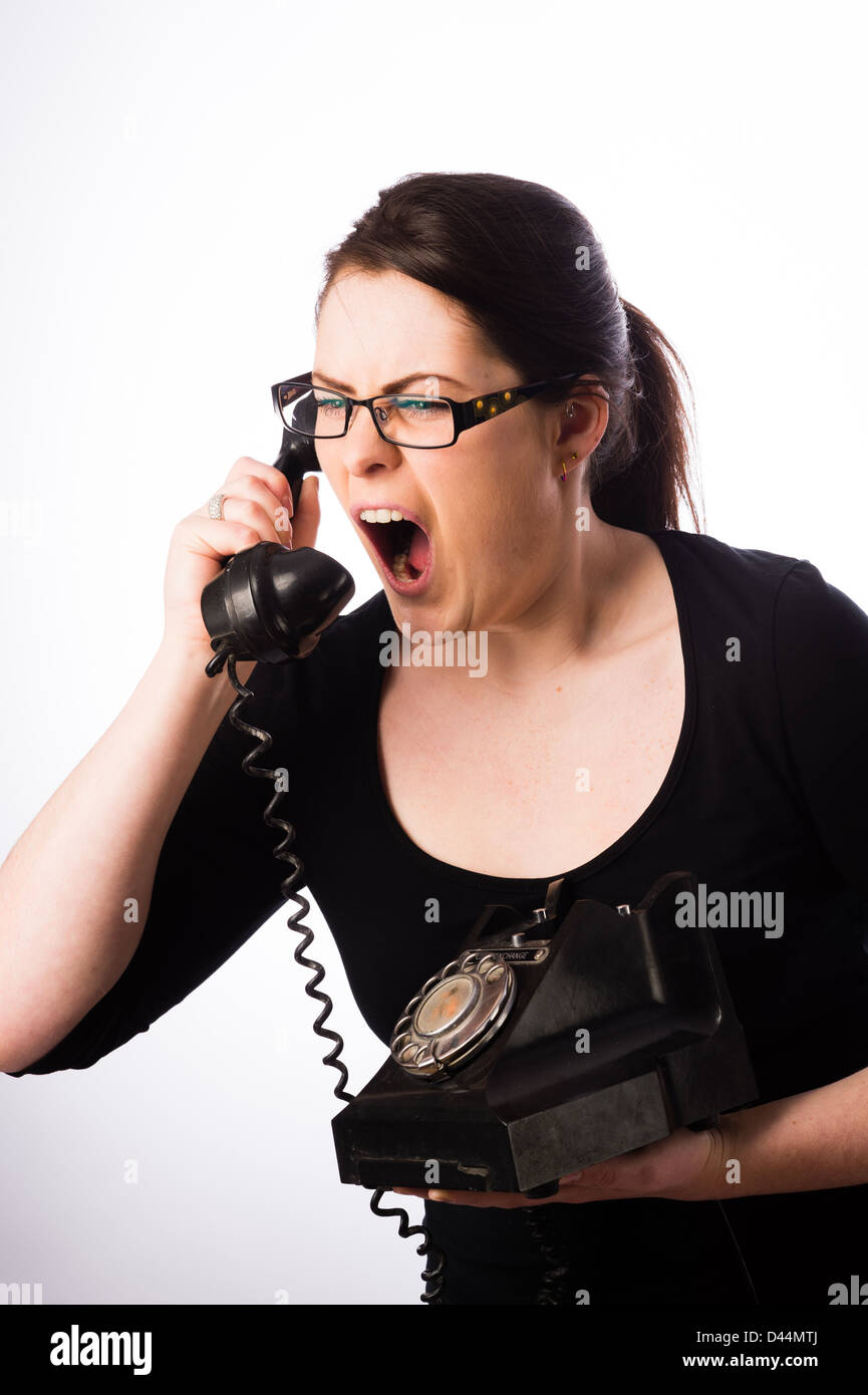 Eine junge Frau, braune Haare, schreien in ein altmodisches Telefon, UK ruft Hilfe Linie Call-Center Stockfoto