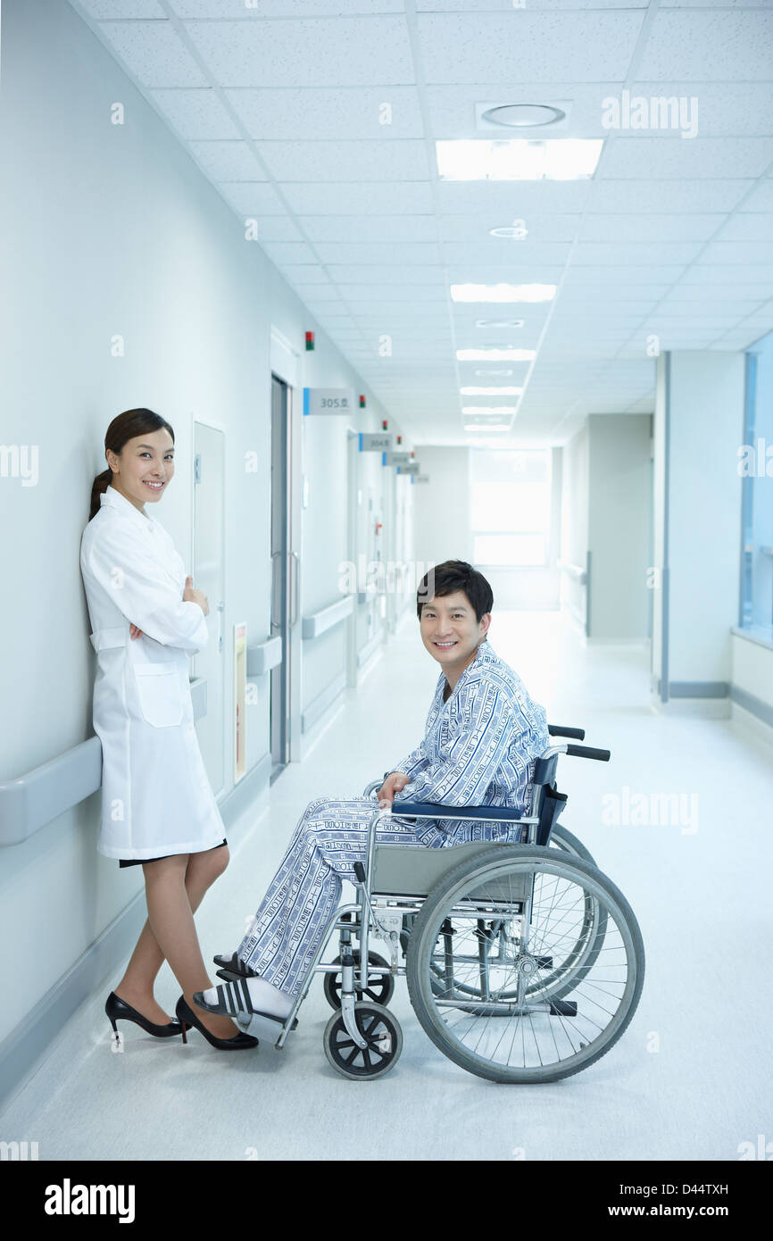 ein Arzt und ein Mann im Rollstuhl auf den Gang des Krankenhauses Stockfoto