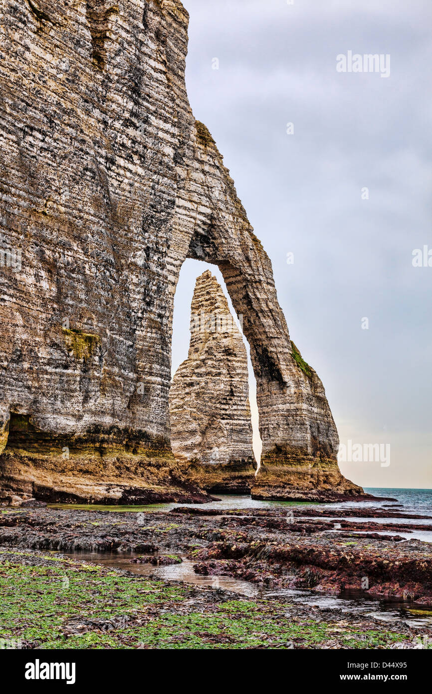 Klippen von Etretat in der oberen Normandie im Norden Frankreichs: eine Nadel Felsen durch einen natürlichen Bogen an den niedrigen Gezeiten gesehen Stockfoto
