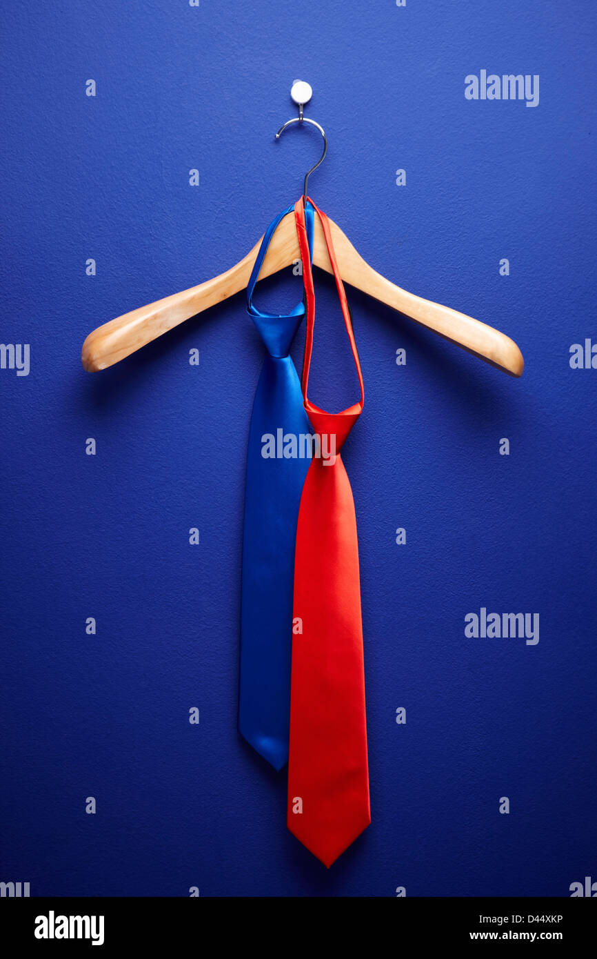 zwei Krawatten hängend auf einem Kleiderbügel in blauem Hintergrund Stockfoto