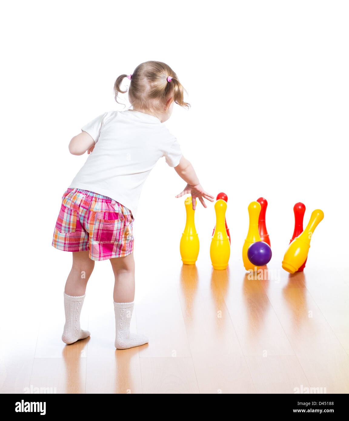Kind wirft Ball niederzuschlagen Spielzeug bowling-Pins. Kind Mädchen steht wieder im Mittelpunkt. Stockfoto