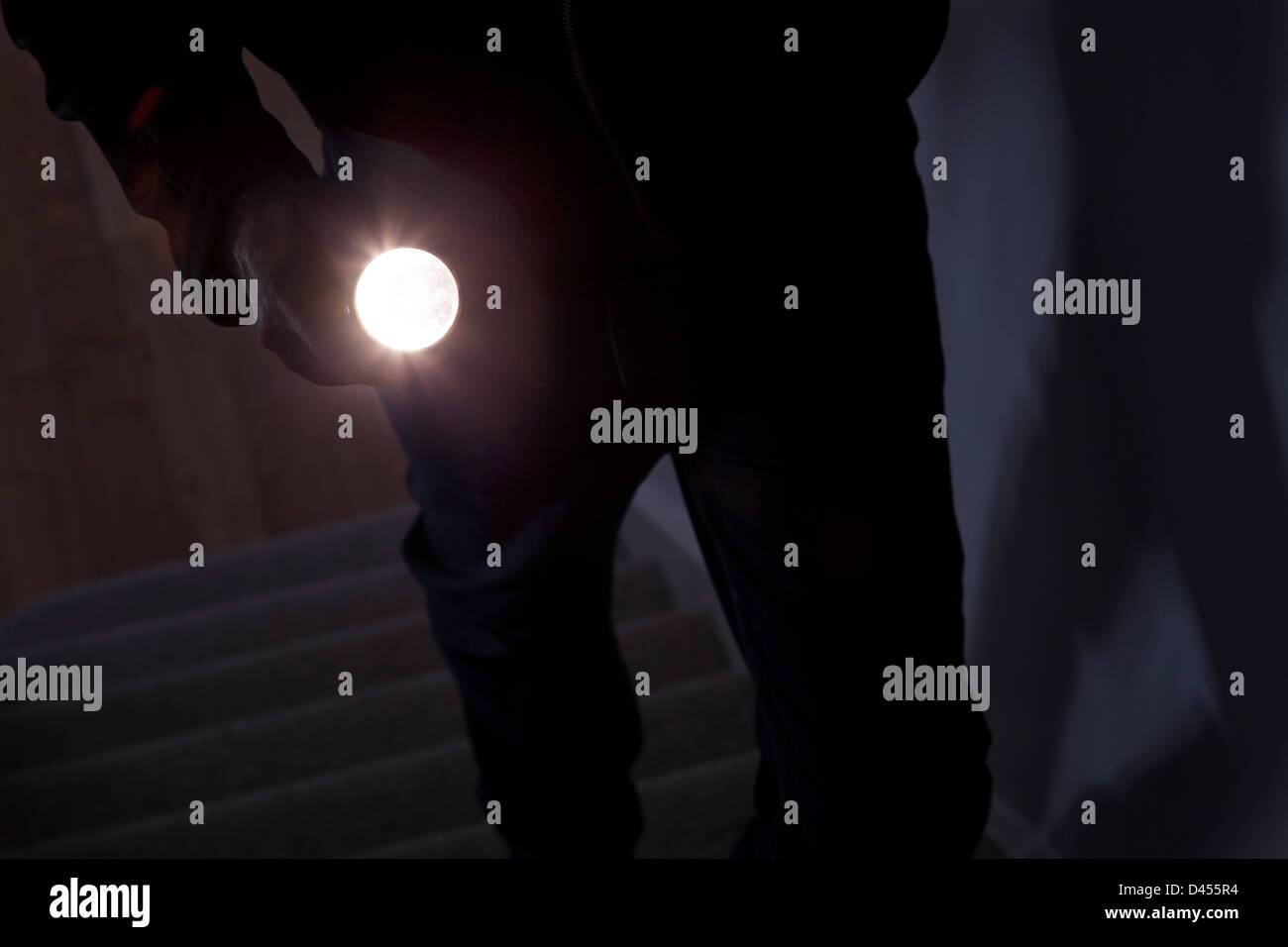 Schattenhafte männlichen Eindringling hält eine Taschenlampe oder Blitzlicht Stockfoto