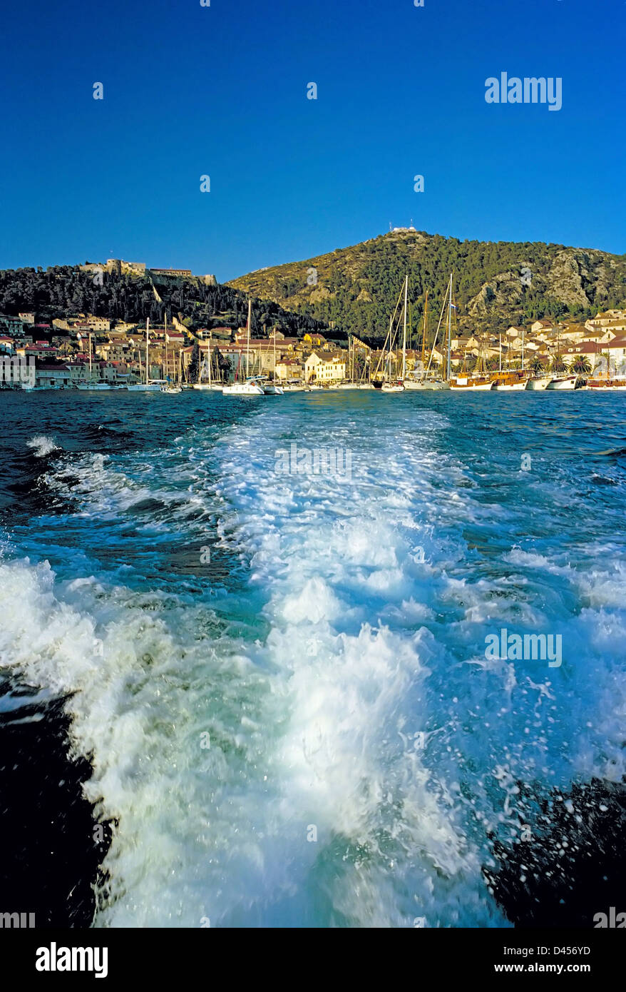 Die mittelalterliche Stadt Hvar aus der dalmatinischen Küste von Kroatien tritt hinter der Wäsche von einem Motorboot Stockfoto