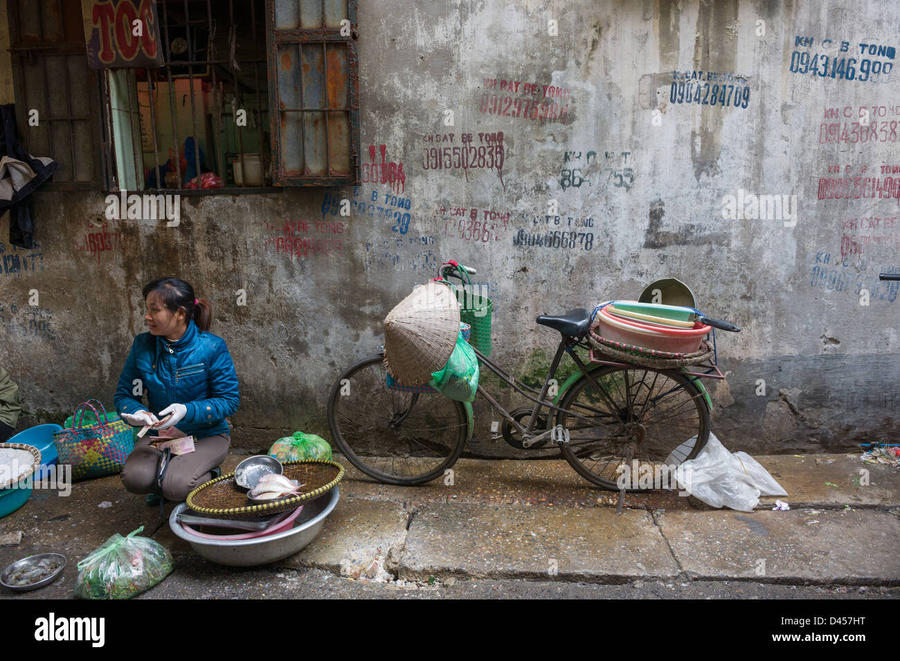 Frau verkaufen Fisch neben ihrem Fahrrad in Ngo Trung Yen Gasse, in der alten Viertel von Hanoi, Vietnam Stockfoto