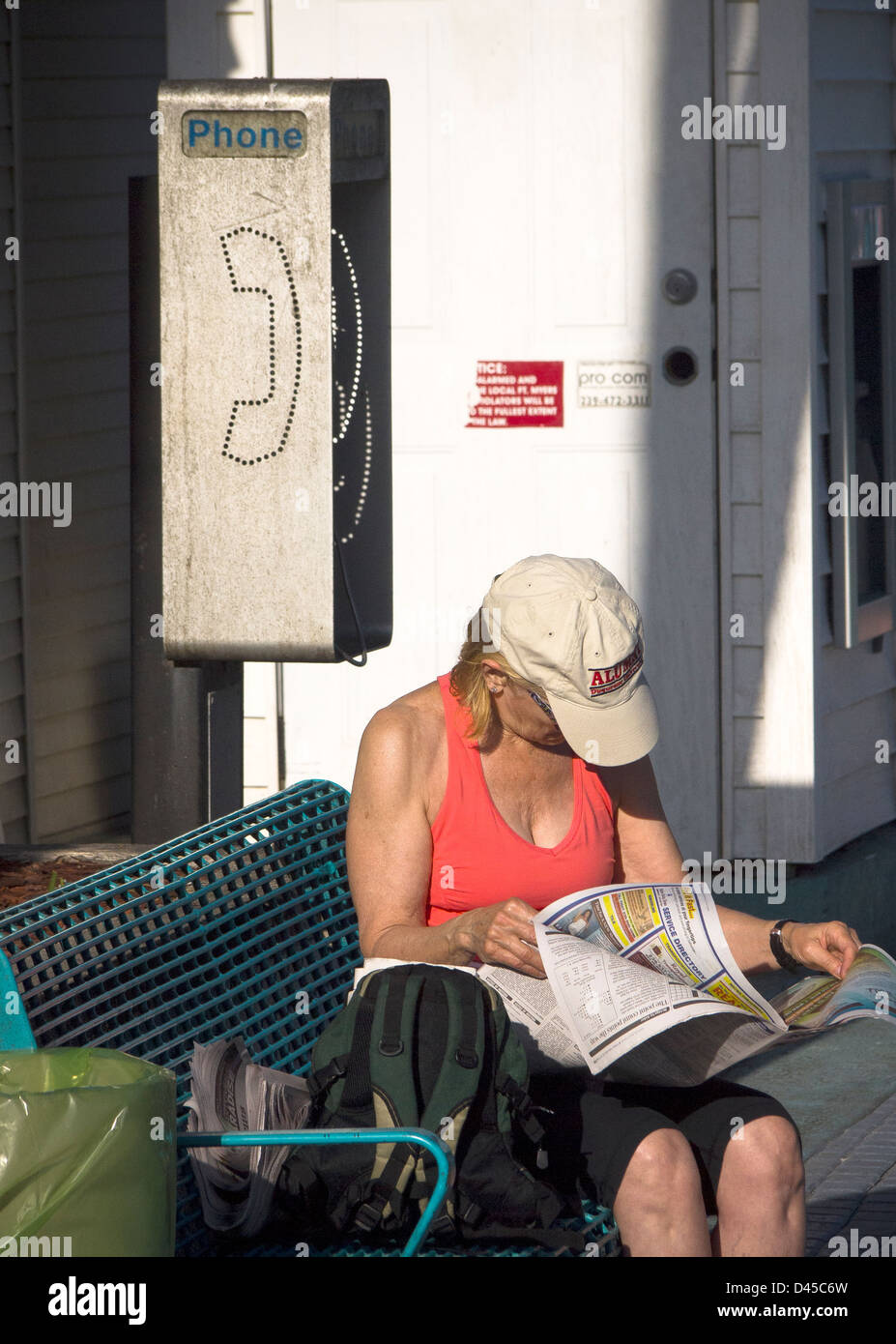Telefonzelle am Florida-Strand mit jemand liest eine Zeitung. Technologie macht diese Szene weniger häufig, wie wir gehen digital Stockfoto