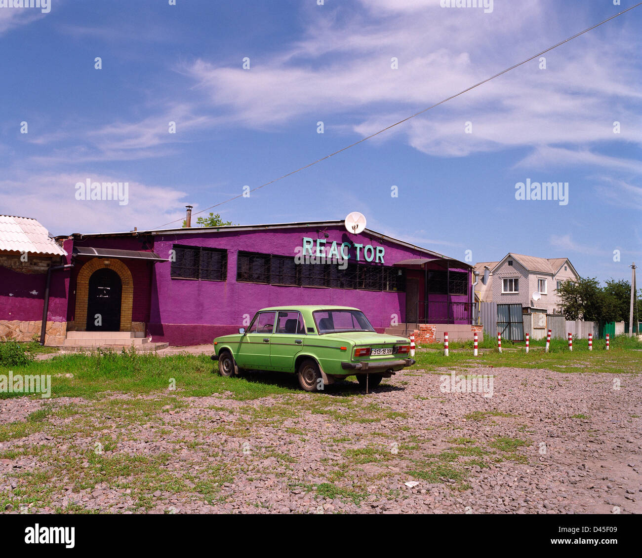 Ein grünes Auto parkt außerhalb eines Magenta Gebäudes. Stockfoto