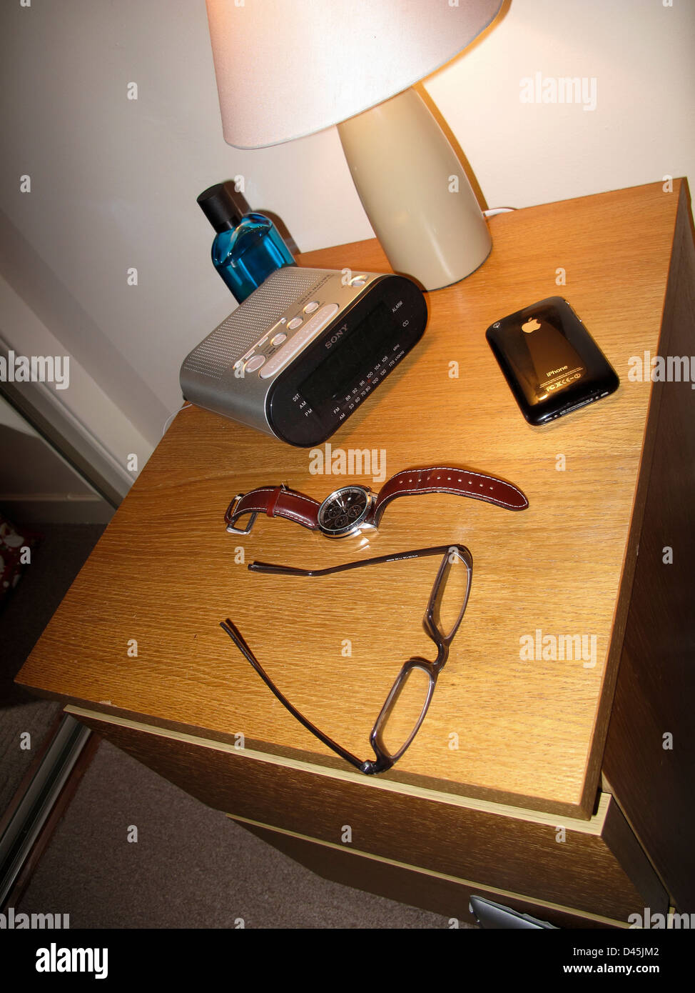 Nachttisch mit Lampe Radiowecker Gläser und iPhone Stockfoto