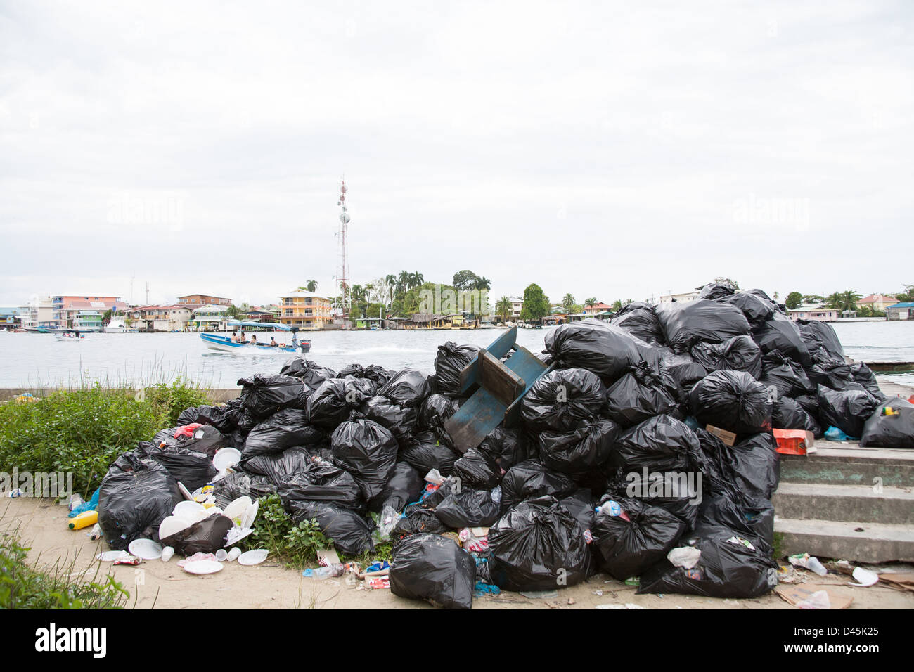 Haufen von Müllsäcke auf Carenero Insel mit Bocas del Toro Town im Hintergrund. Stockfoto