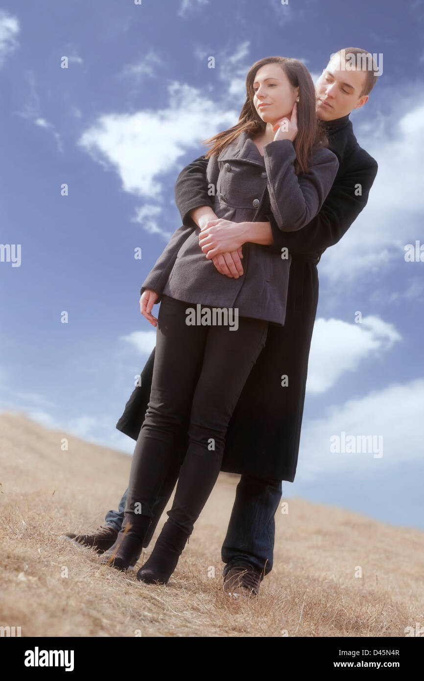 ein Mann umarmt seine Freundin auf einer Wiese Stockfoto
