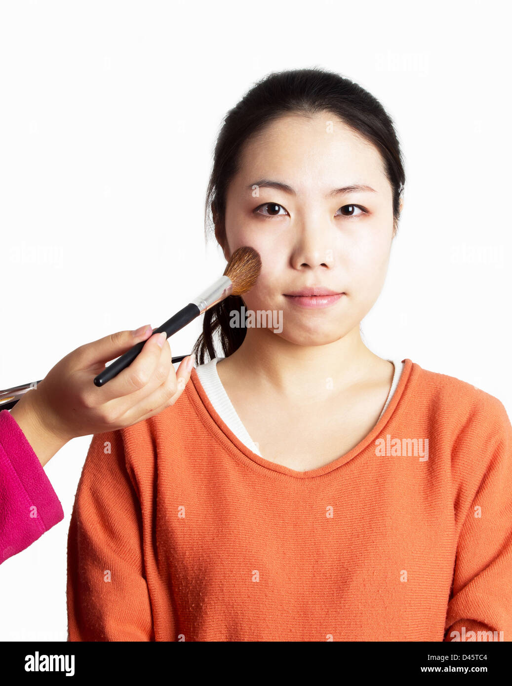Asiatische Frau, die Röte, die durch eine Kosmetikerin angewendet Stockfoto