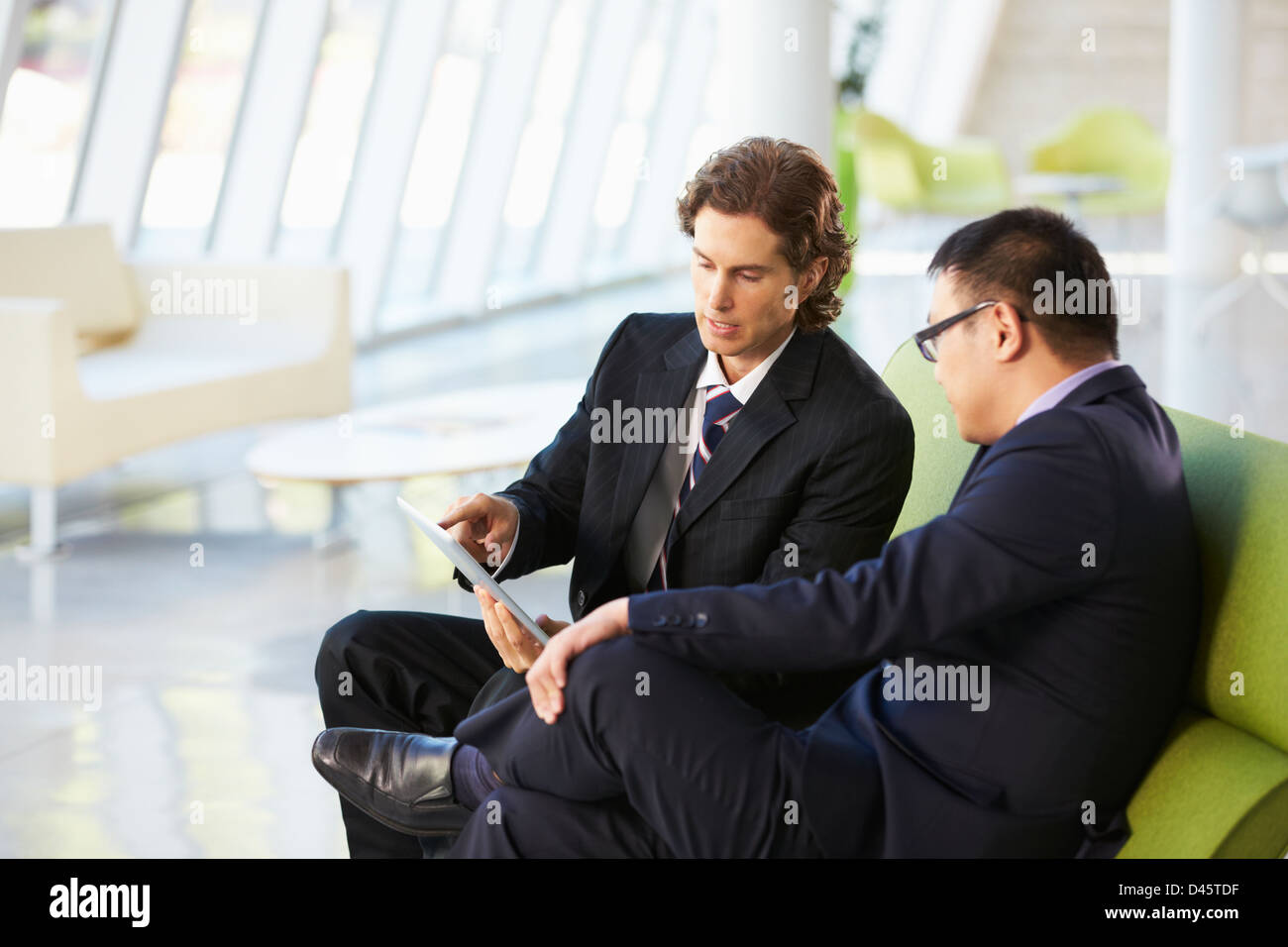 Geschäftsleute mit Digital-Tablette sitzen im modernen Büro Stockfoto