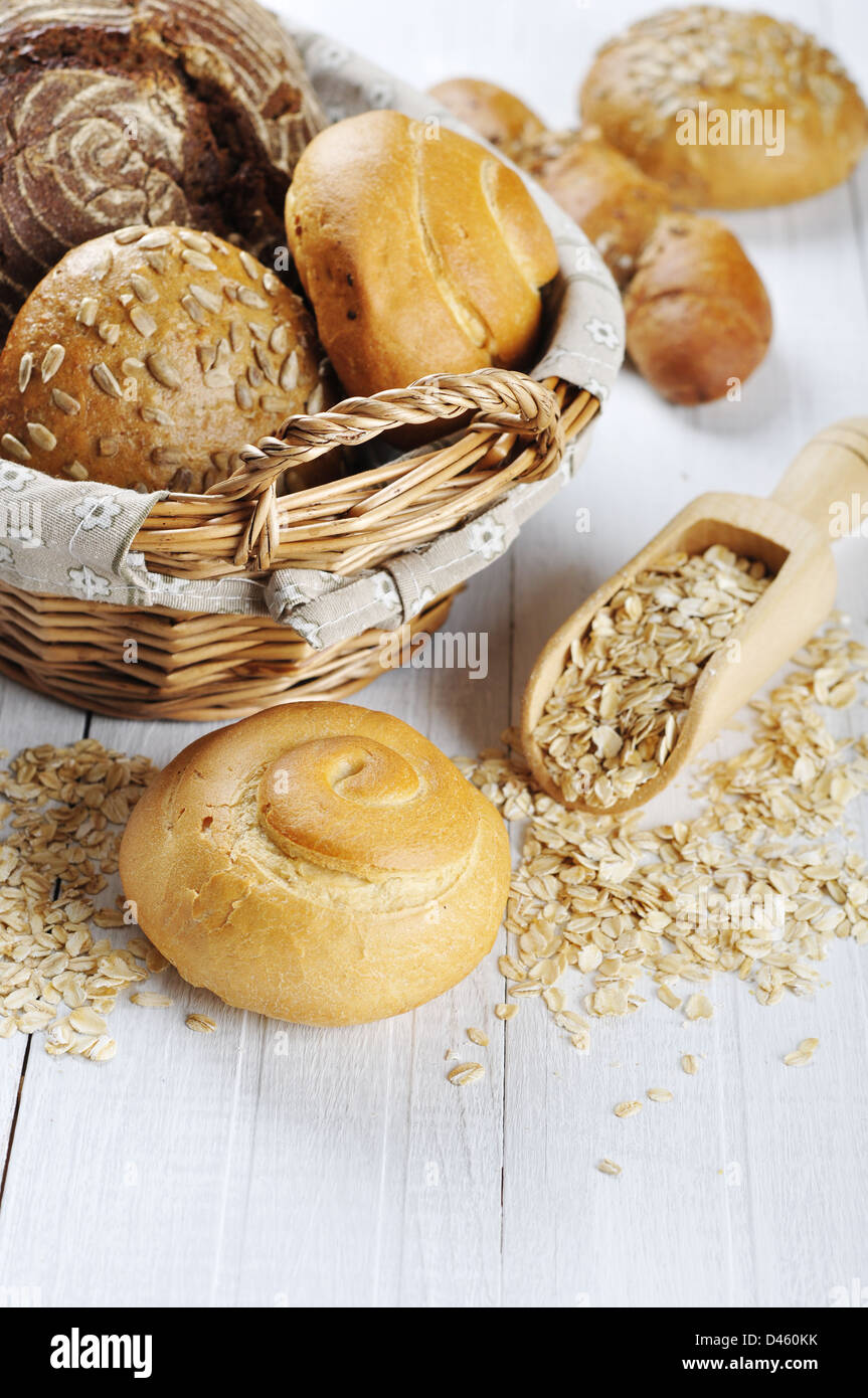 Komposition mit Brot und Brötchen im Weidenkorb über weißem Holz Hintergrund Stockfoto