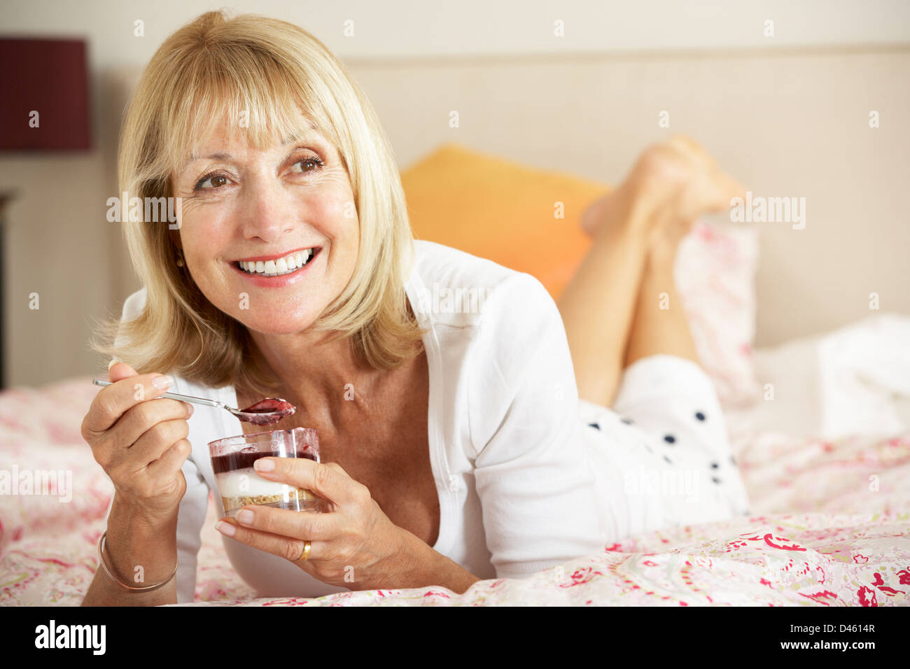 Ältere Frau Essen Dessert im Bett Stockfoto