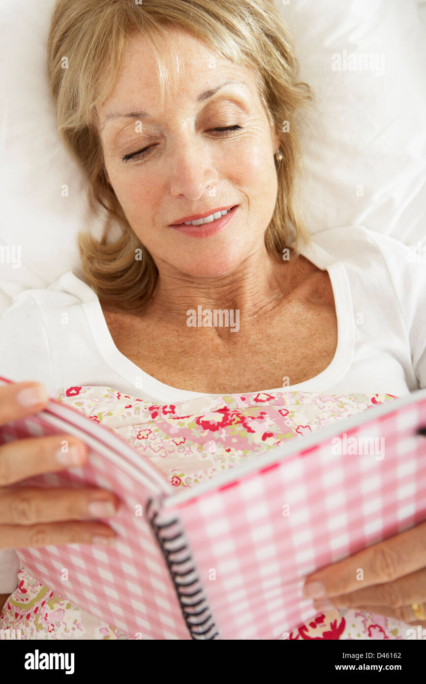 Ältere Frau im Bett lesen Tagebuch Stockfoto