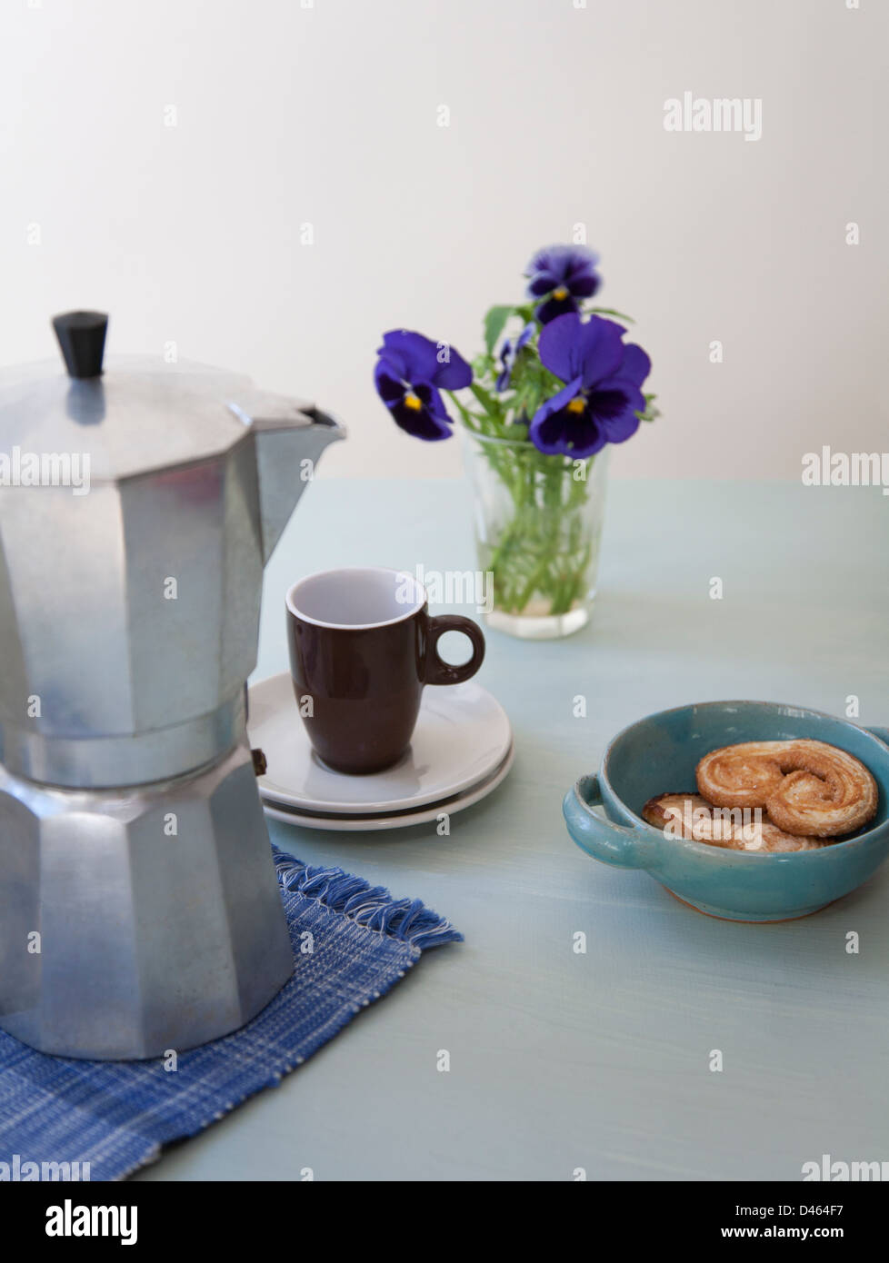 Pausenzeit mit Herd Kaffeemaschine, Espressotasse, Herz-Form-Gebäck und eine Vase mit Blumen Stockfoto