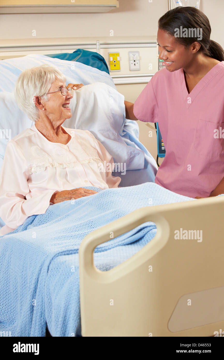 Krankenschwester im Gespräch mit älteren Patientin im Krankenhausbett Stockfoto